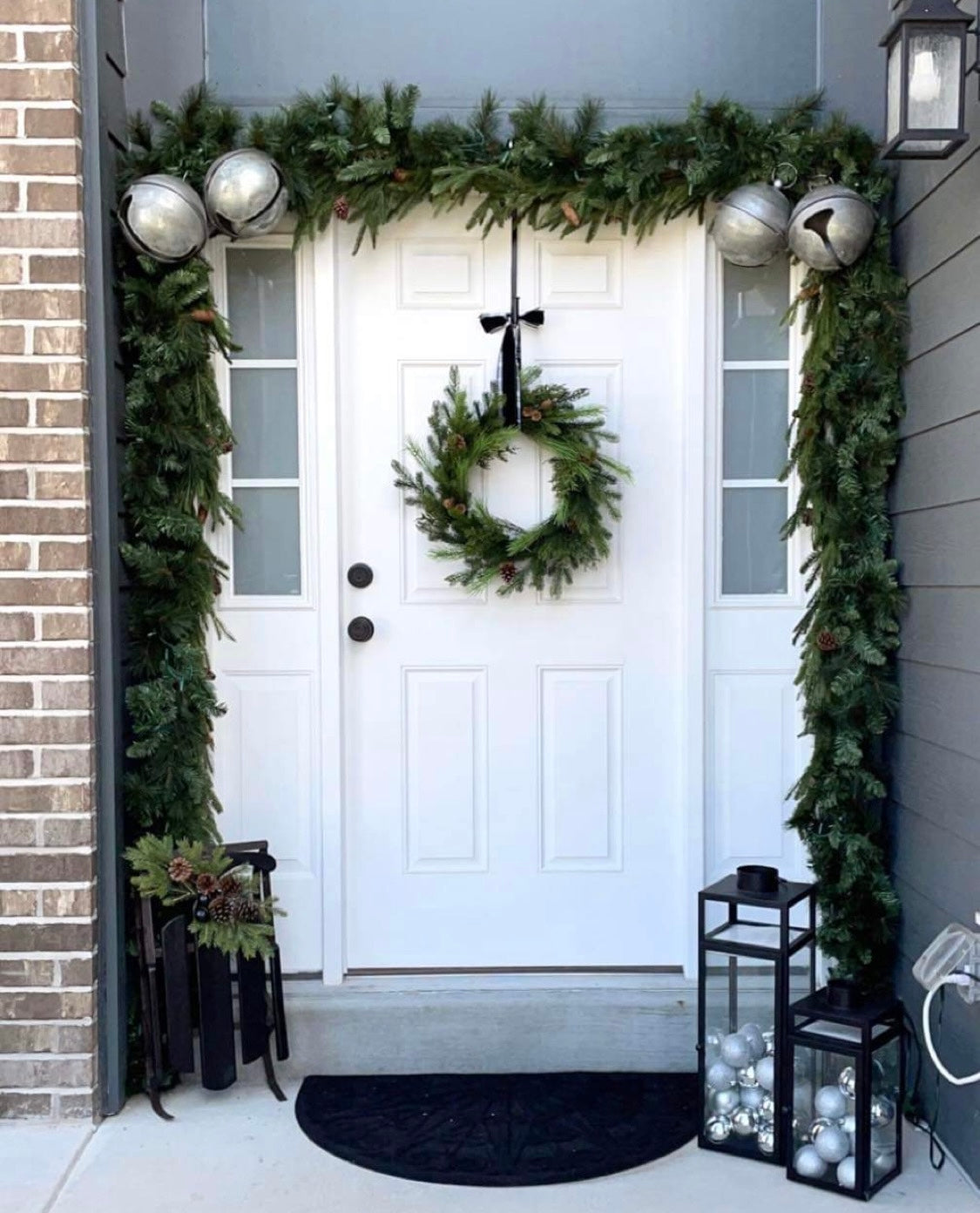 oversized-metal-christmas-holiday-bells-above-a-white-door-with-green-garland
