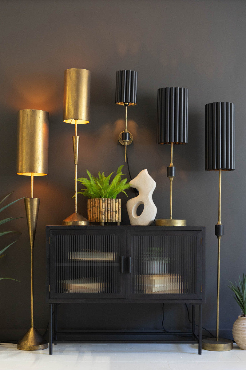 five gold and black metal lamps with shads on black wall in living room with green plant