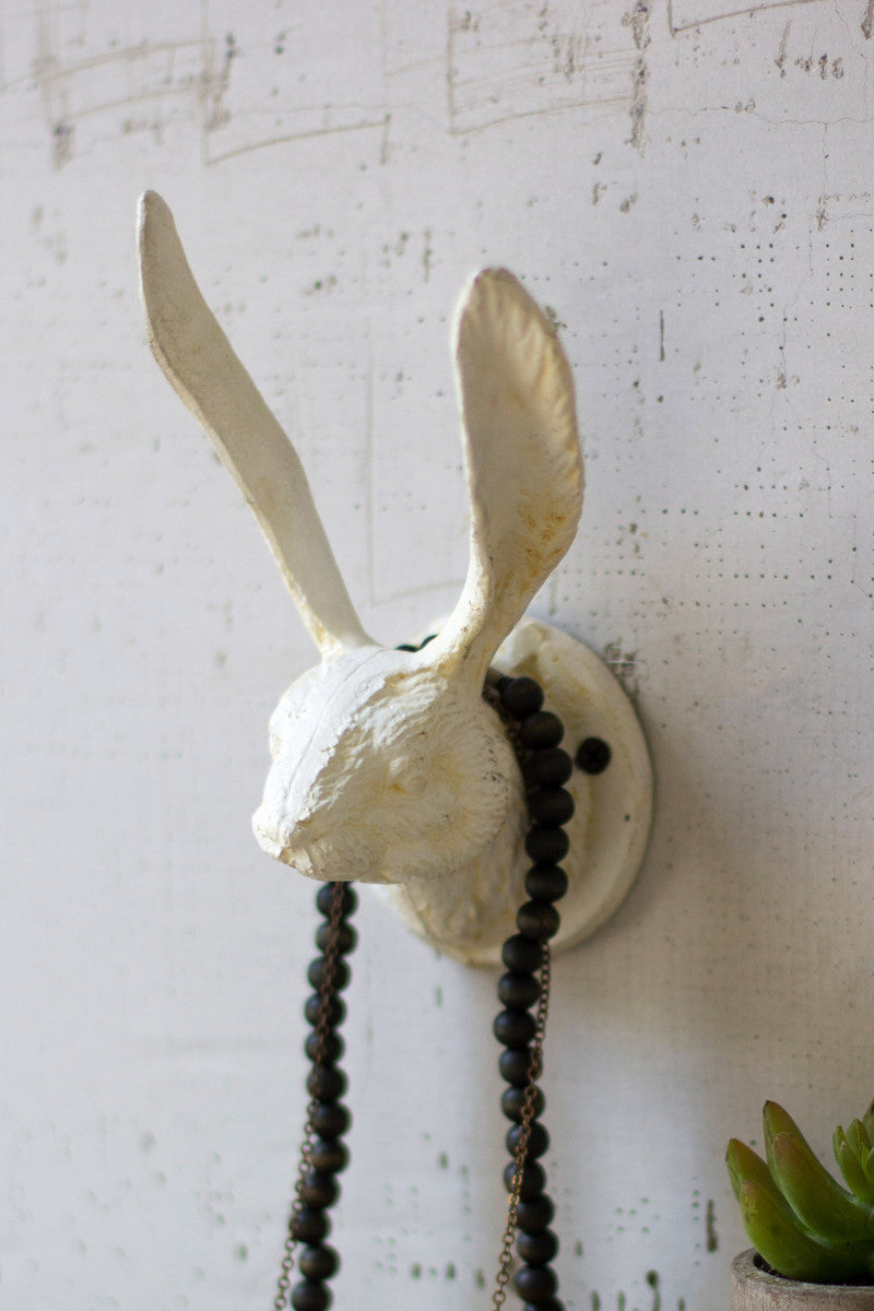 antique white bunny rabbit wall hook for towels or jewelry on a white wood wall with green plant