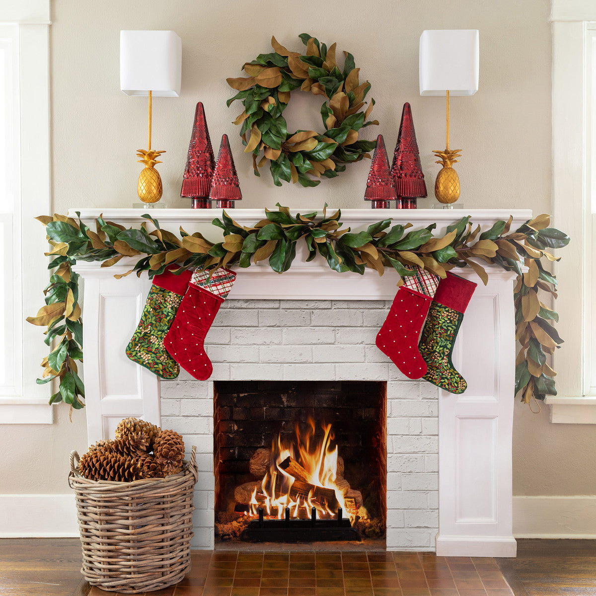 handwoven rattan floor basket with pine cones white mantle fireplace magnolia garland wreath and red and green stockings
