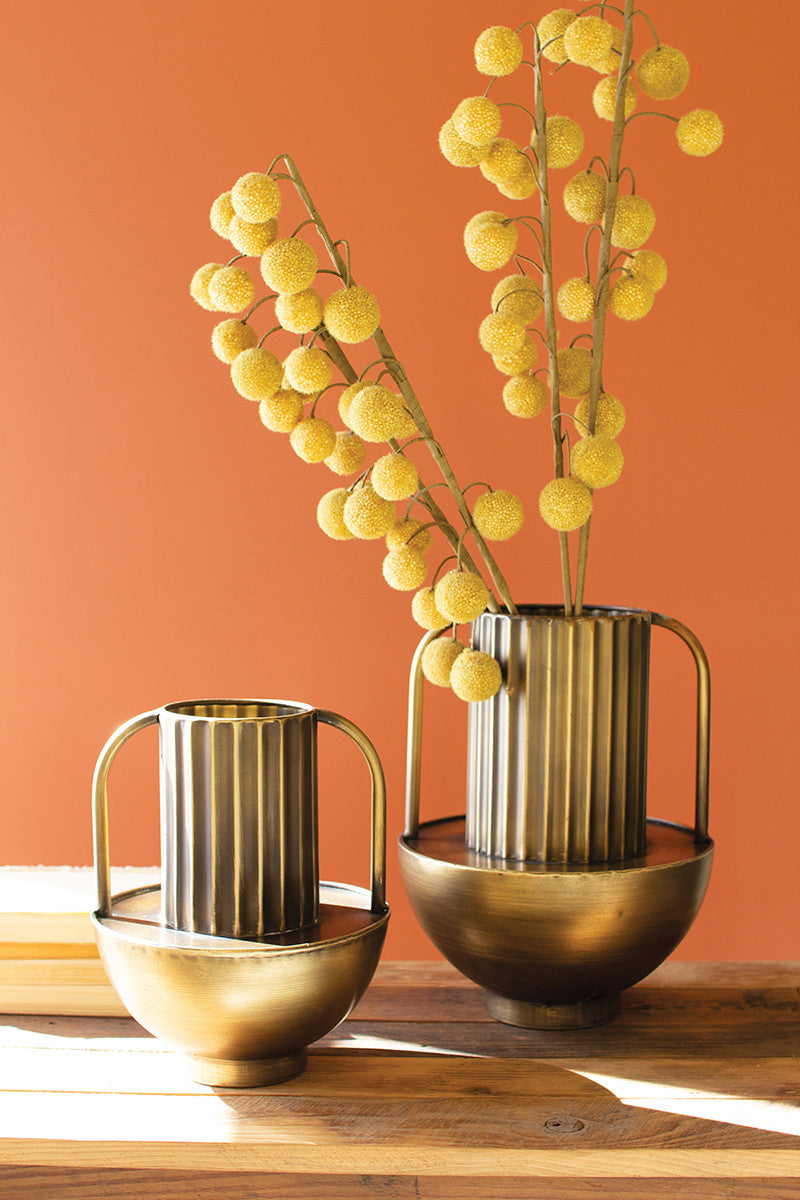 two metal gold brass vases with handles and yellow modern flowers on orange wall