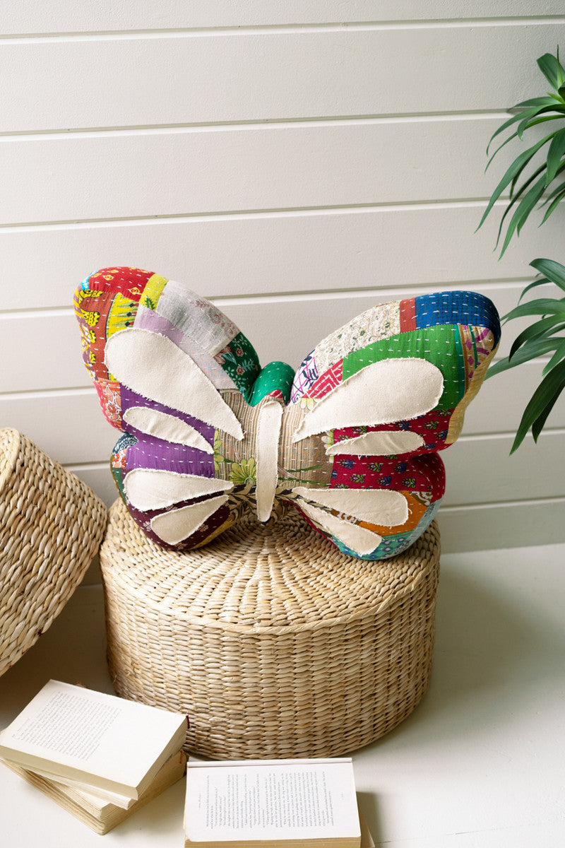 colorful boho butterfly pillow on wicker basket white walls and books