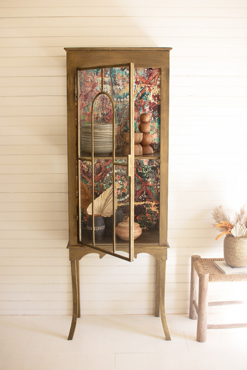 display cabinet with colorful print backing  styled on white wall with dishes and decor