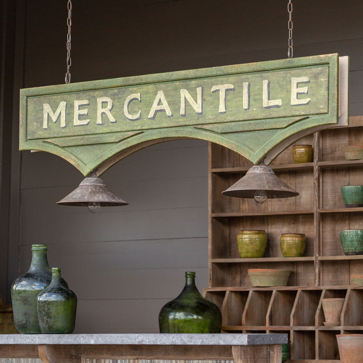 distressed green iron mercantile light fixture hanging from ceiling