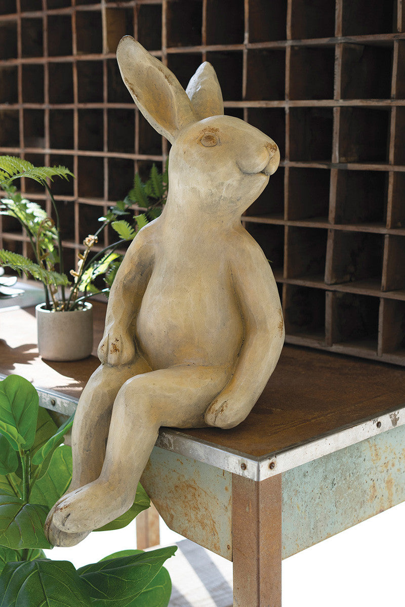 faux concrete rabbit sitting on table with green plants in office