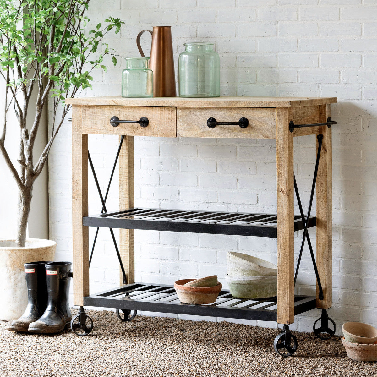 wood and metal potting cart with wheels with rain boots pots vases and watering cans