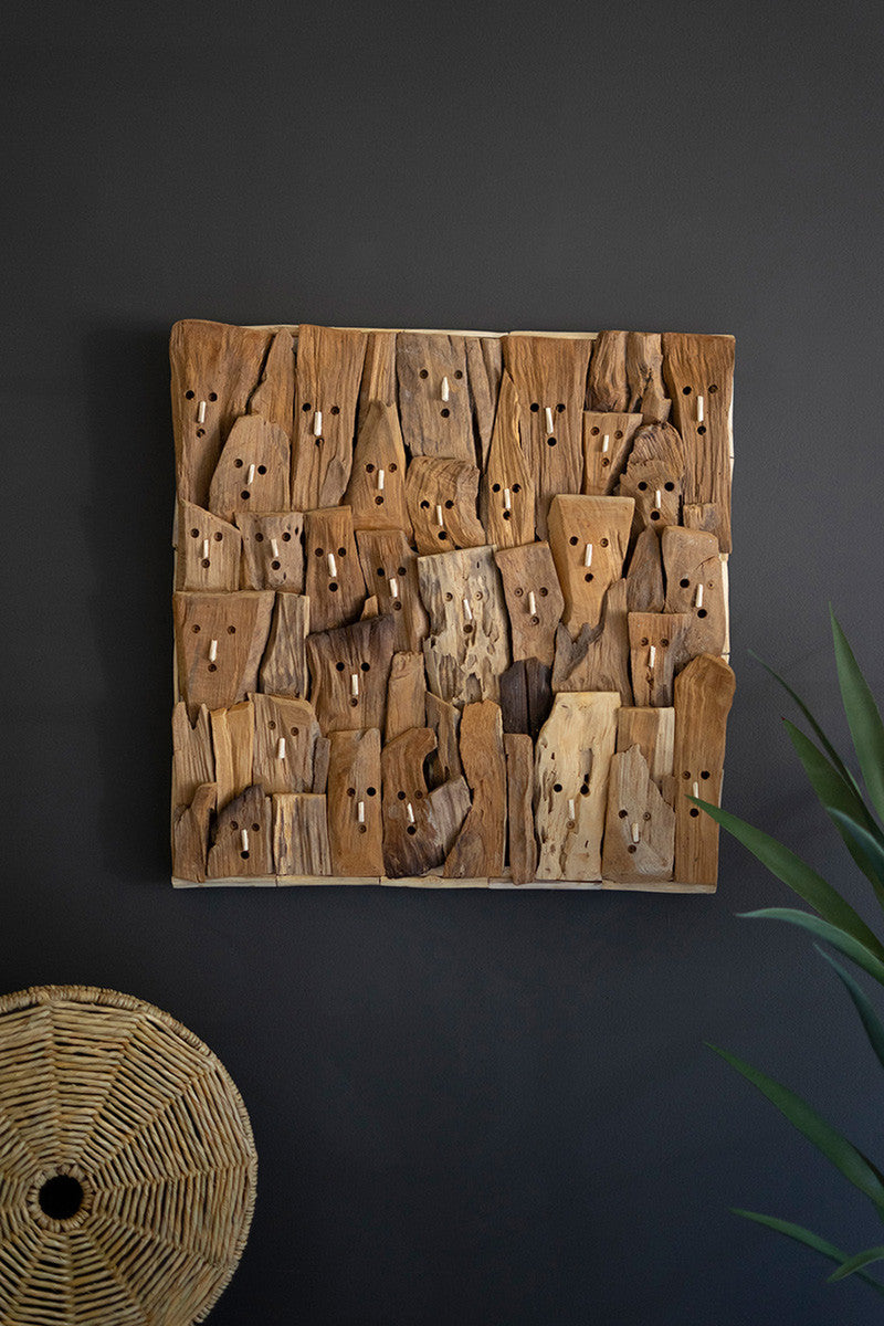whimsical driftwood face wall art on dark wall with basket and plant