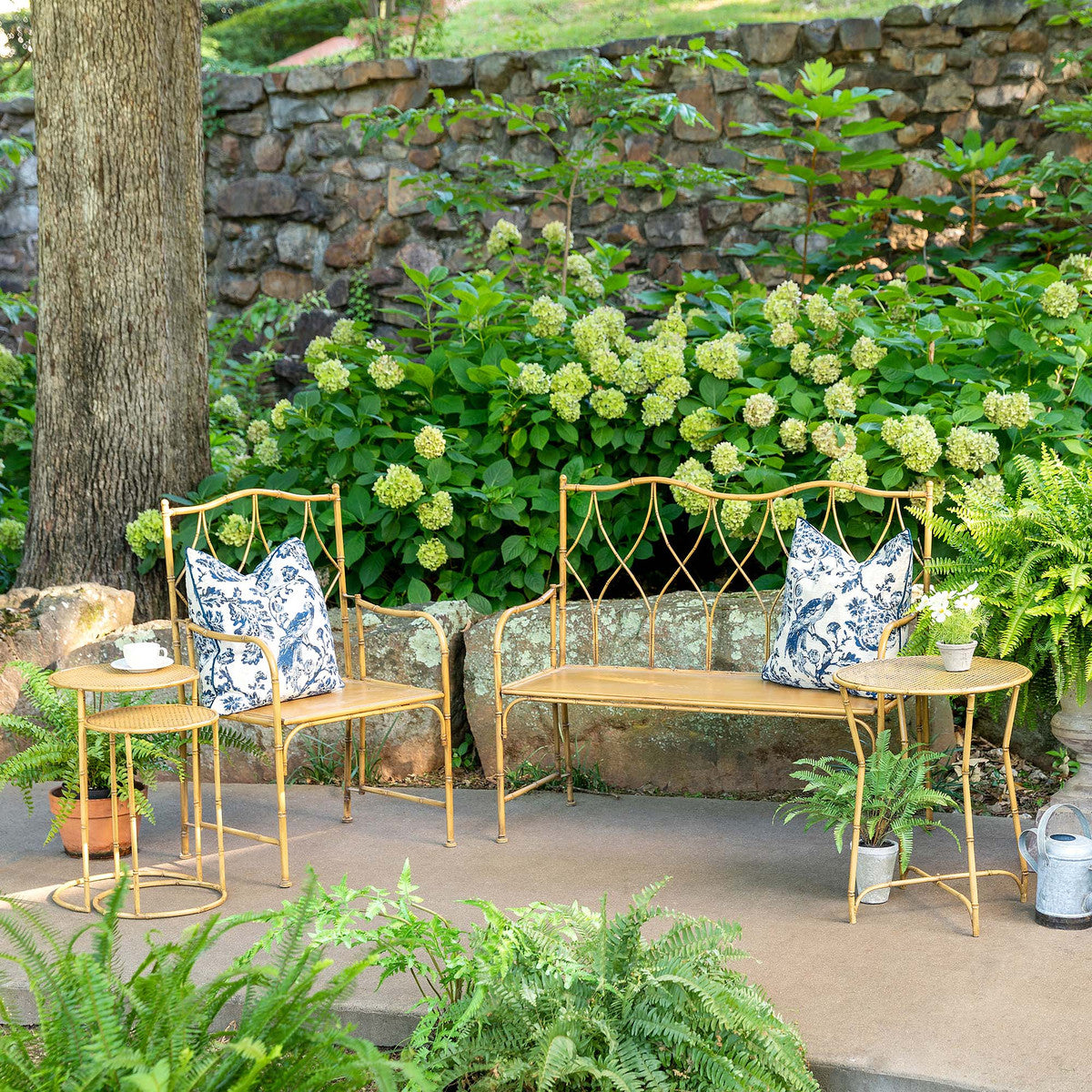 outdoor patio with green blooming hydrangea and a metal furniture  set with couch table and chair