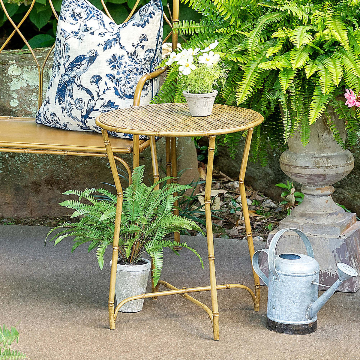a metal table in an outdoor patio setting with a real kimberly queen fern and  artificial blooming plants