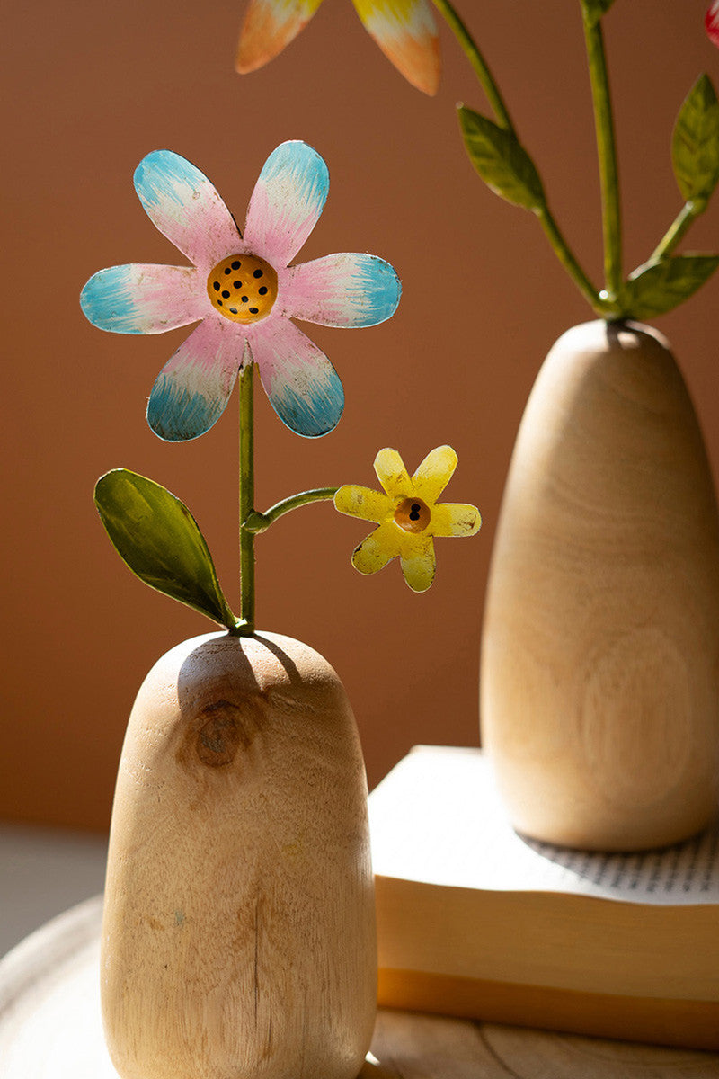colorful metal flower in wood vase on books
