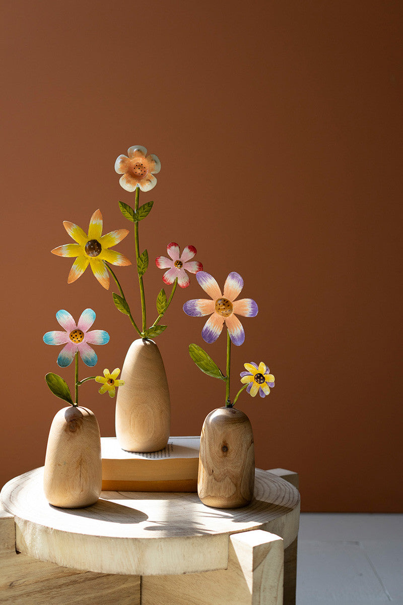 colorful metal flowers in three wood vases on table 