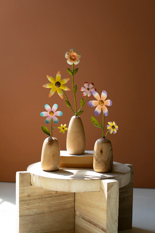 whimsical metal and wood flowers in wood vase on table with sun shining in