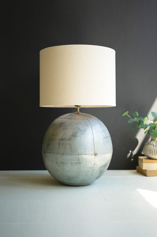 unique round iron metal table lamp with fabric shade on table with plant and books
