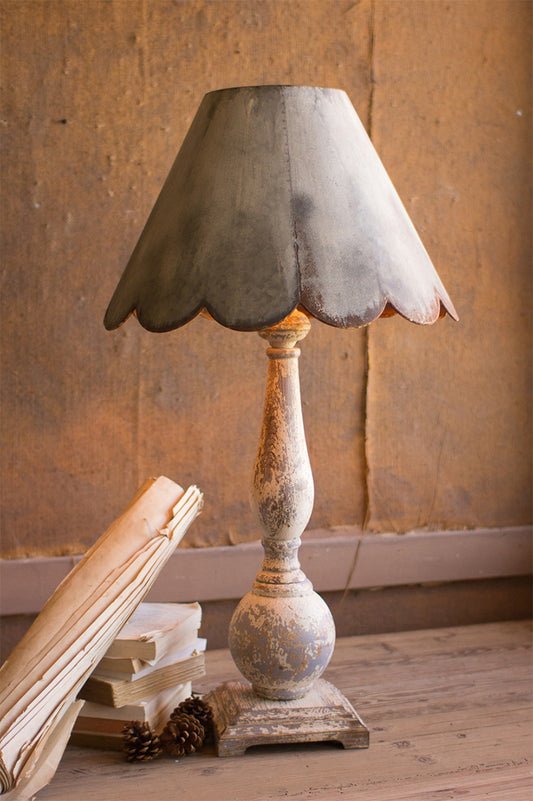 a rustic table lamp with a scallop edge shade styled with three pine cones and neutral colored books