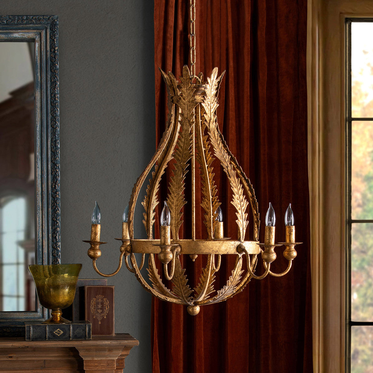 gold luxury chandelier in front of velvet curtains and a window