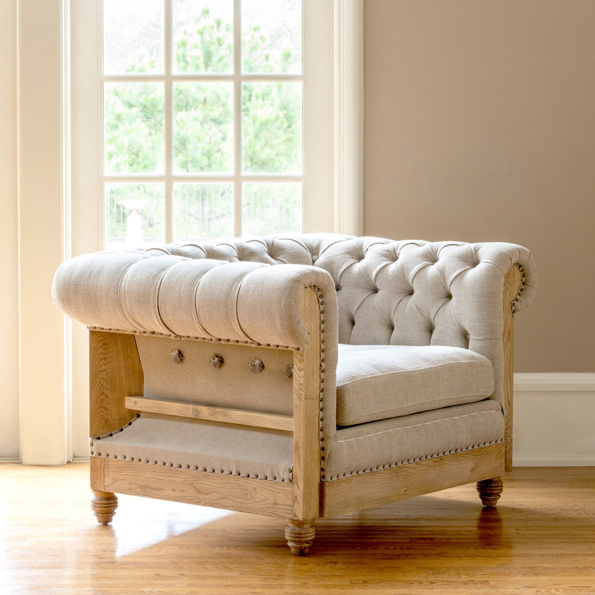 tufted chair in front of a window with hard wood floors