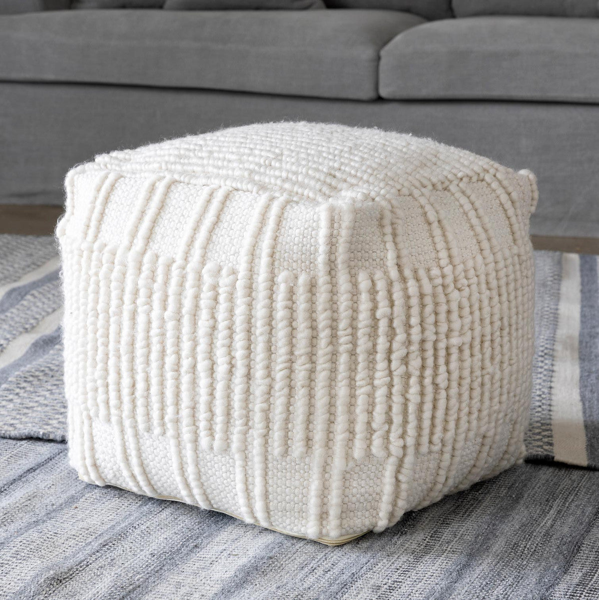off white pouf on blue-gray rug and couch