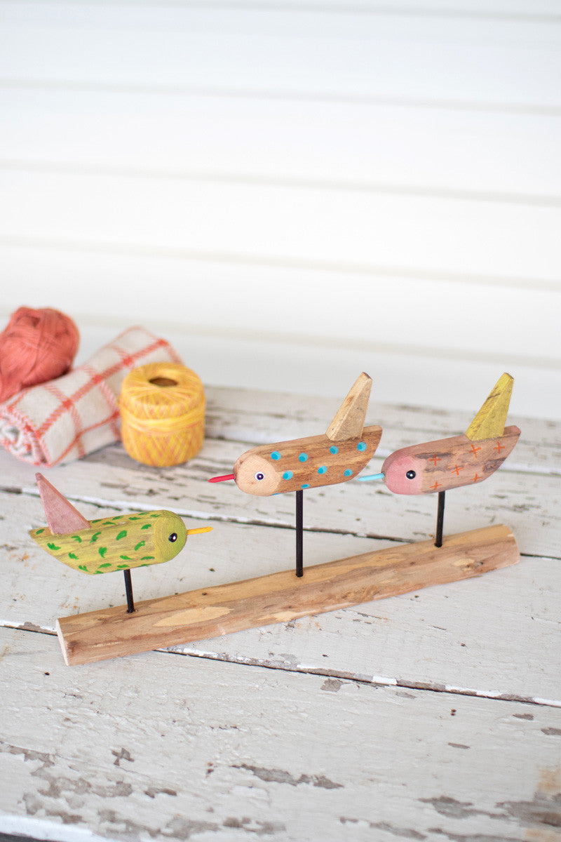 three painted wooden birds on a base