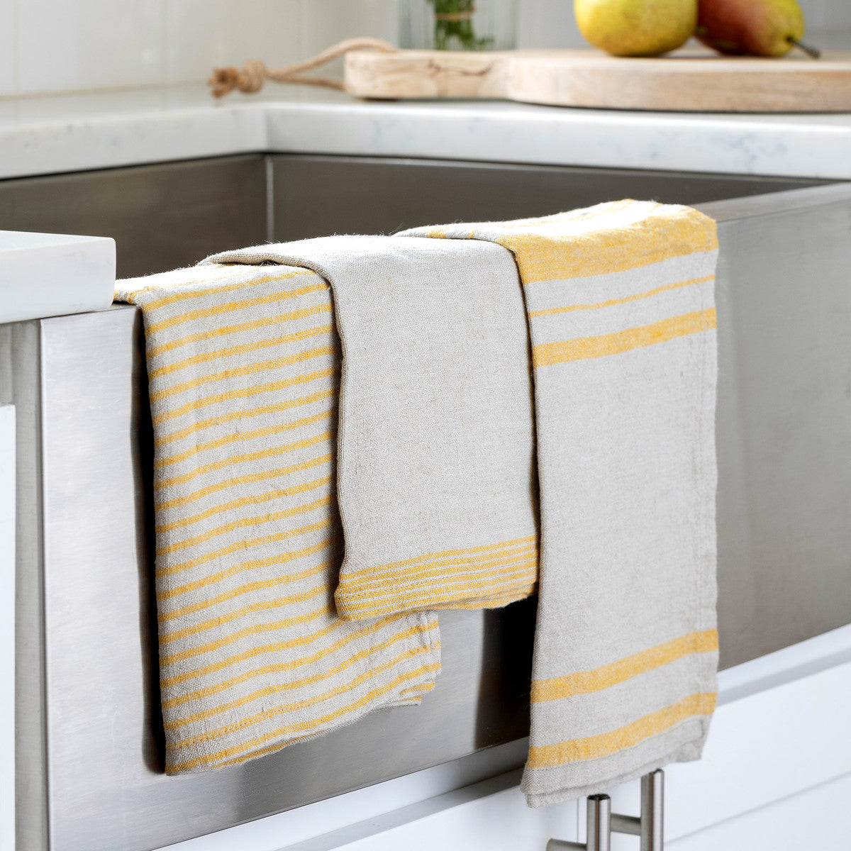three soft yellow linen dish towels on  sink