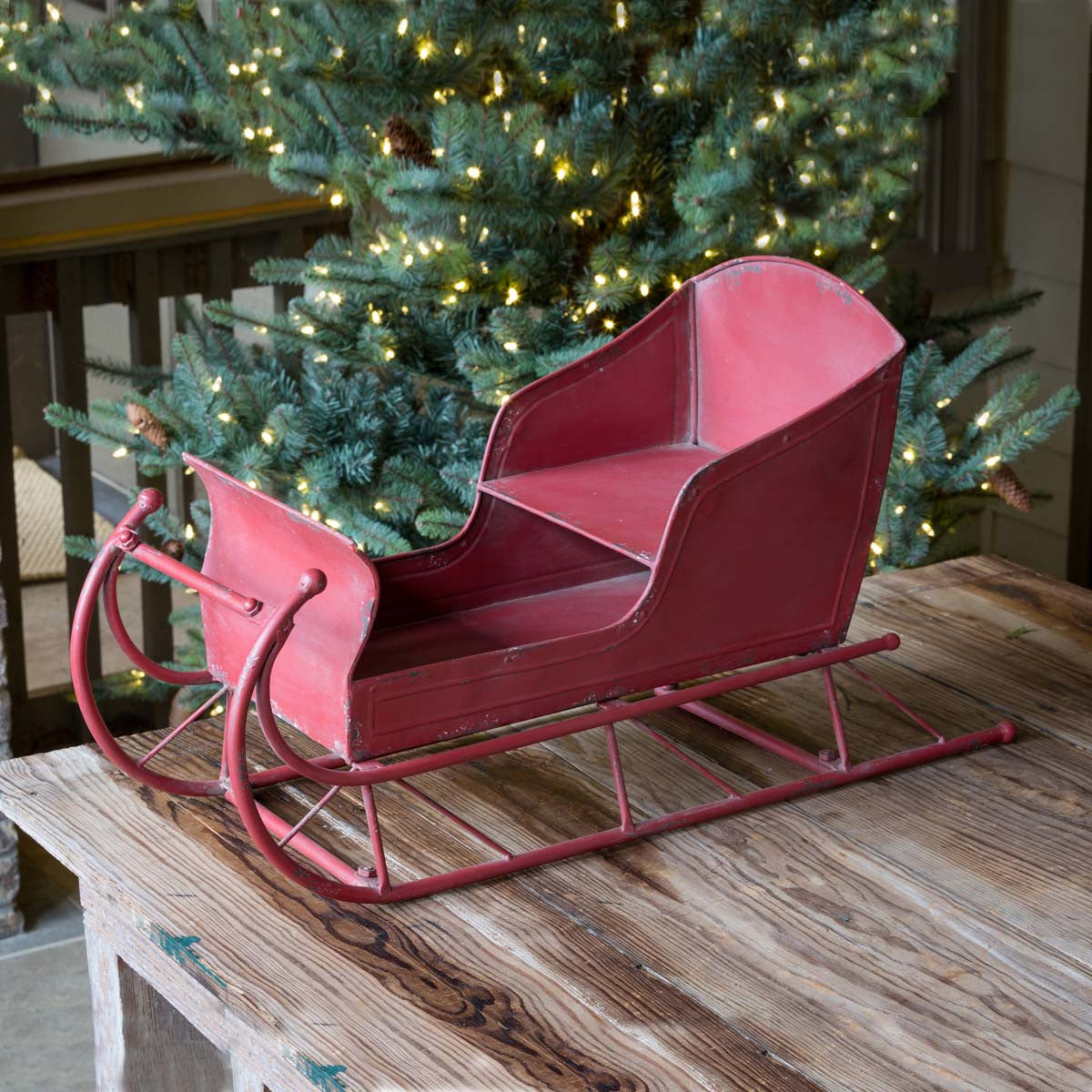 red-metal-vintage-sleigh-in-front-of-green-christmas-tree-with-lights